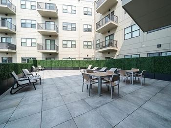 A patio with a table and chairs is in front of a building at Crossroads 389 Apartments, Hackensack